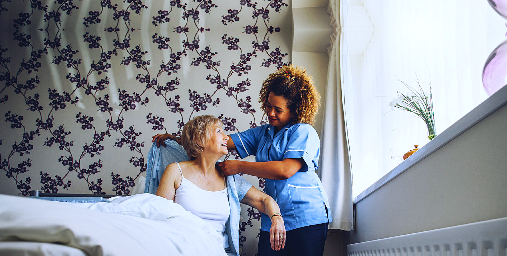 caregiver assisting senior woman in bed
