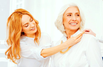adult woman assisting senior woman in dressing