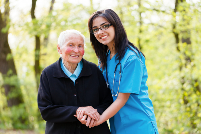 Portrait of caring nurse helping elderly lady holding her hands.